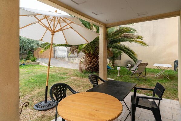 A patio area with a table and chairs, an umbrella, and a palm tree.