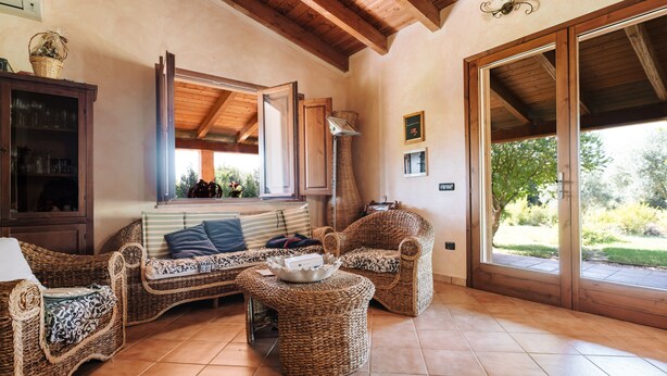 A cozy living area with wicker furniture, a tiled floor, and a large sliding glass door leading to an outdoor space. - Villa 'Casa Serra' with Mountain View, Wi-Fi and Air Conditioning (Pimentel)