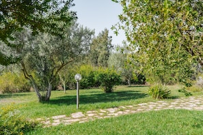 A garden with a stone pathway, trees, and a metal lamp post.