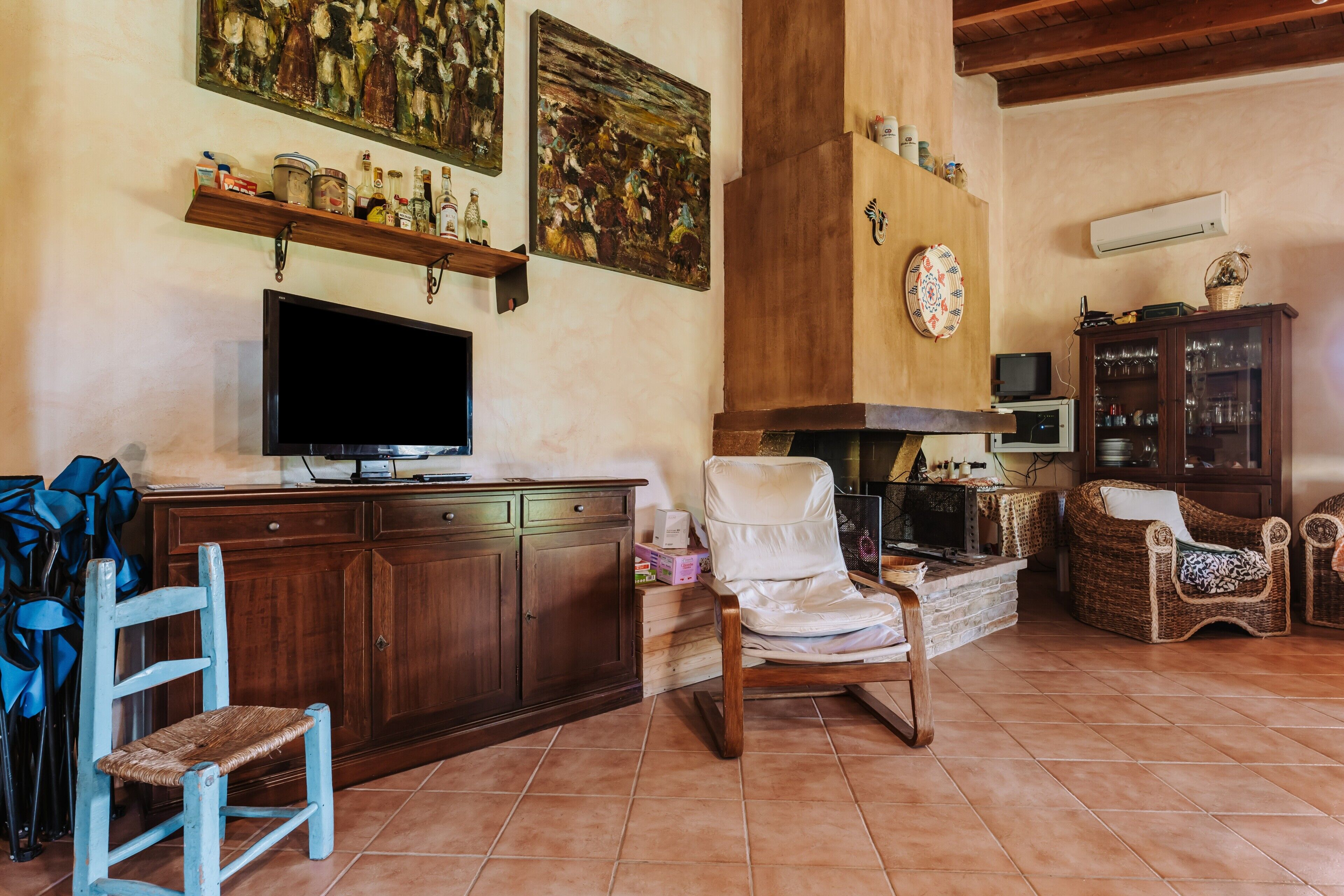 Un salón con televisor, muebles de madera, chimenea y obras de arte en las paredes.