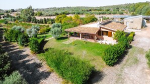 A house with a tiled roof, a covered patio, and a garden with various plants and trees. - Villa 'Casa Serra' with Mountain View, Wi-Fi and Air Conditioning (Pimentel)