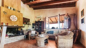 A cozy living room with a fireplace, wicker furniture, and a tiled floor. - Villa 'Casa Serra' with Mountain View, Wi-Fi and Air Conditioning (Pimentel)