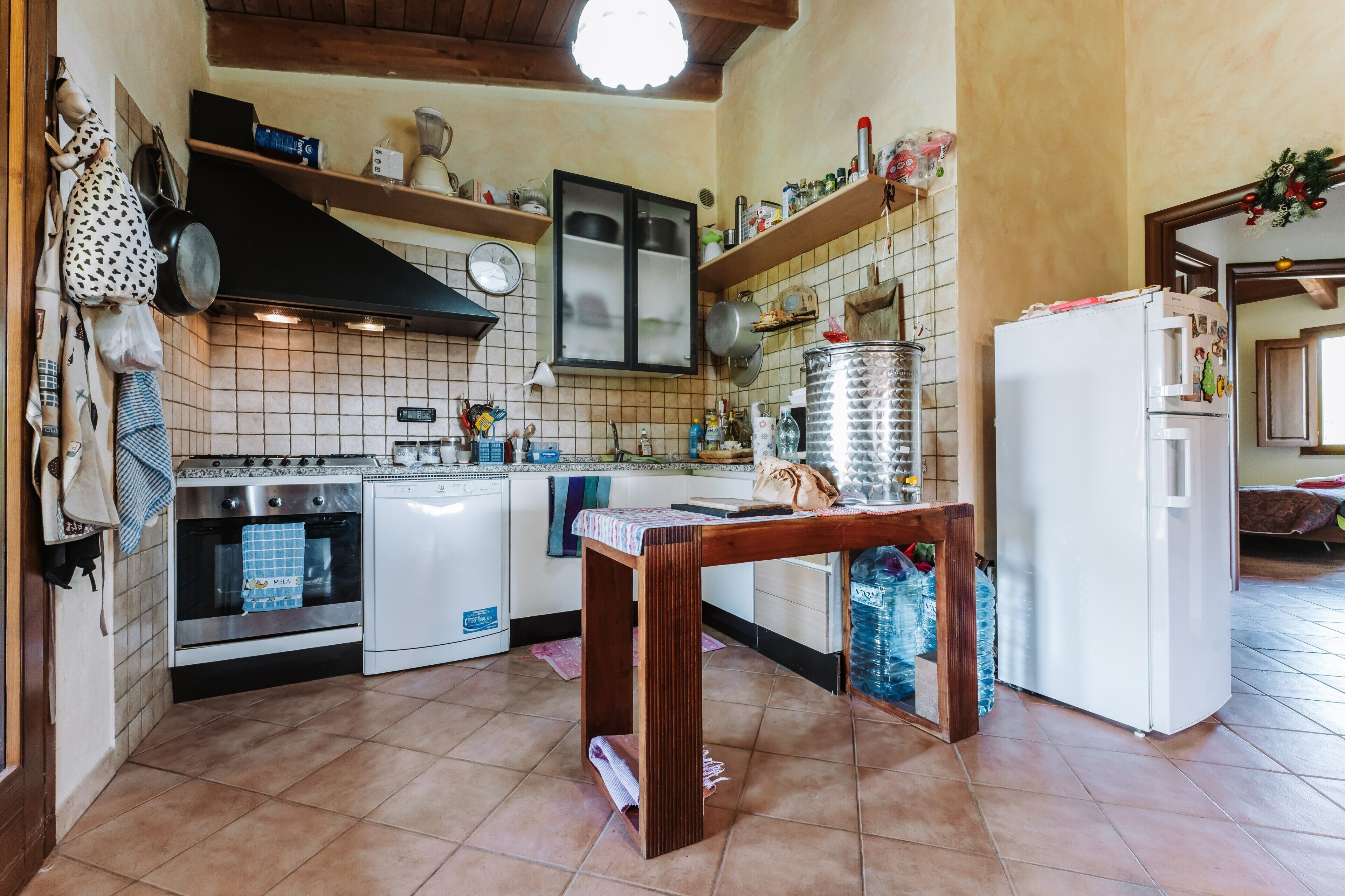 A kitchen with a stove, oven, refrigerator, and a wooden table.