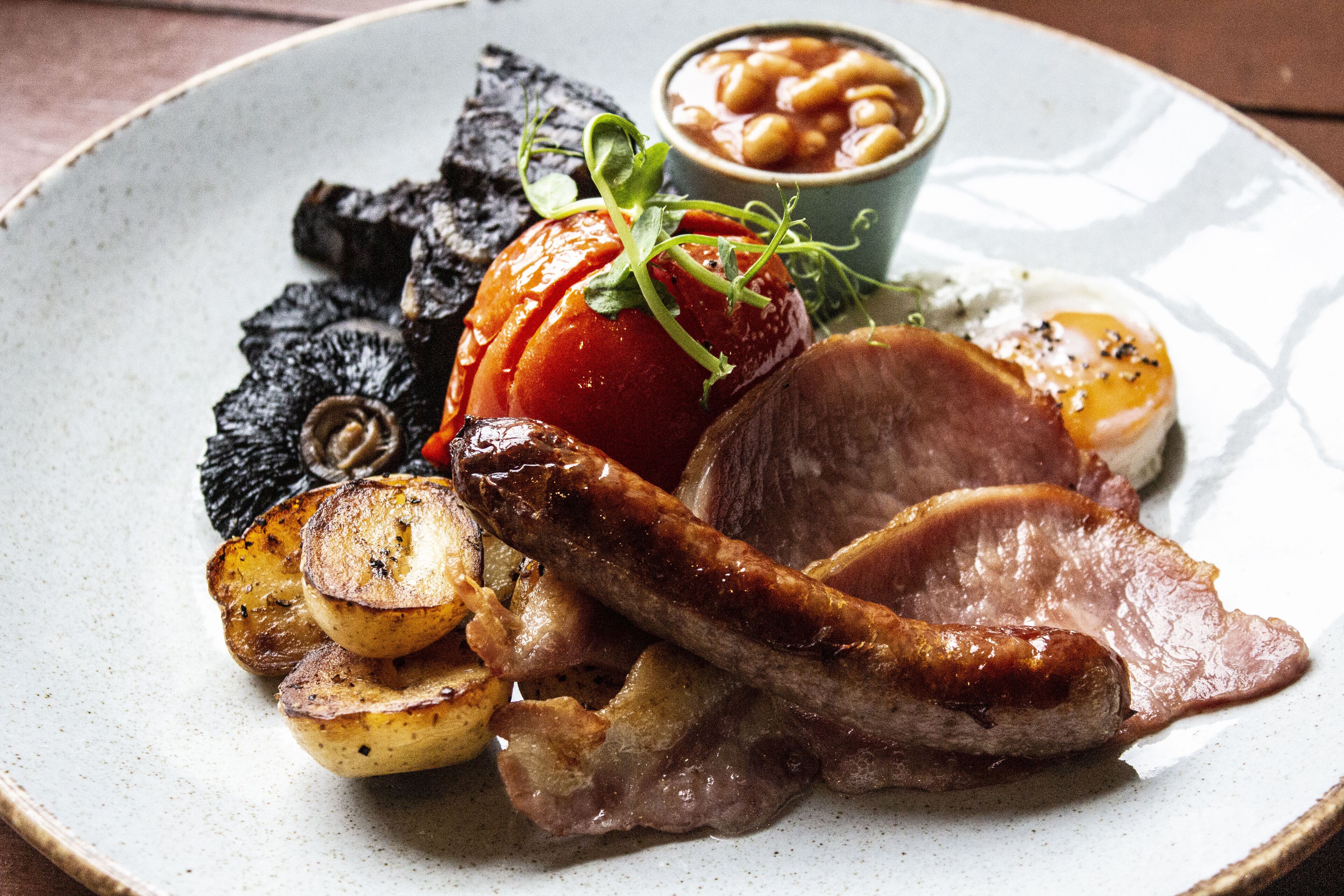 Un piatto con carne arrosto, patate e fagioli.