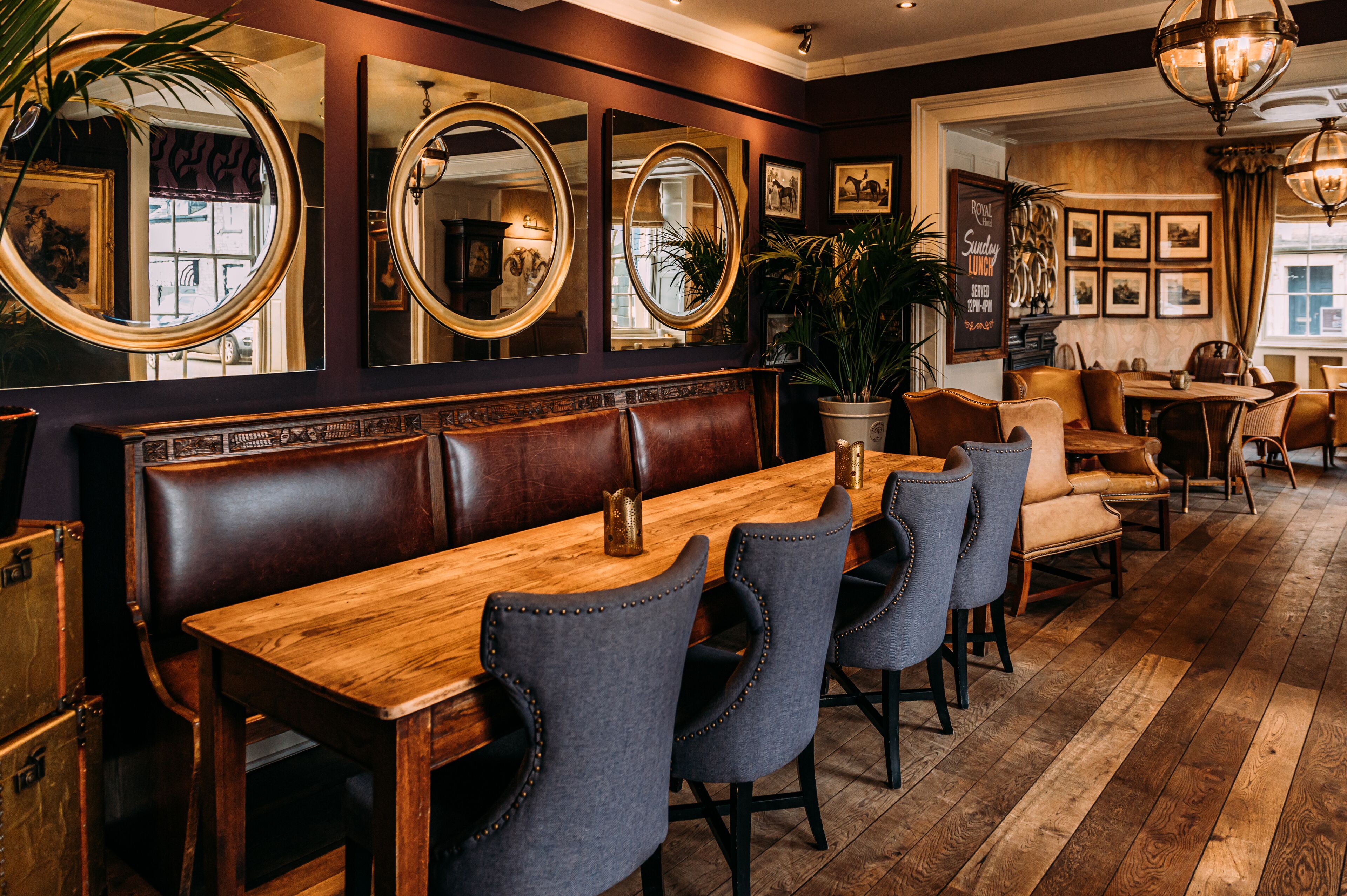 A restaurant with a wooden table, leather booth seating, and multiple mirrors on the wall.
