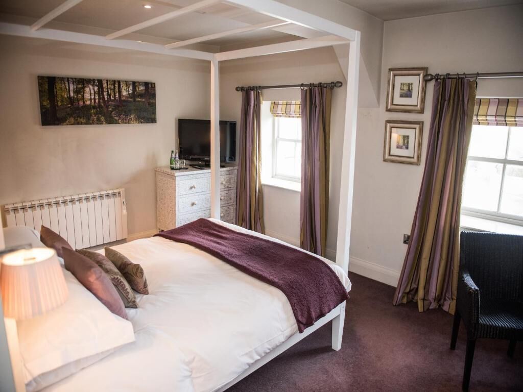 Ein Schlafzimmer mit Bett, Fernseher, Kommode und Stuhl.