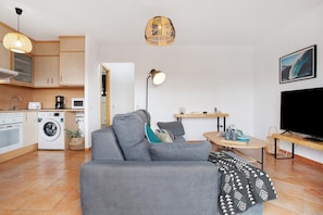 Un appartement moderne comprenant une cuisine, un espace de vie avec un canapé, une table à manger et un téléviseur.