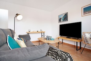 Un salon avec un canapé, une table basse, un téléviseur, une lampe et un tableau encadré au mur.
