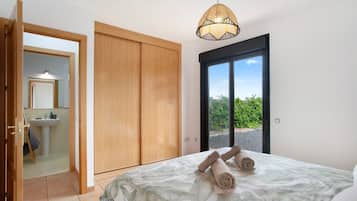 Una camera da letto con un letto, una lampada a sospensione, una porta scorrevole e vista su del verde all'esterno.