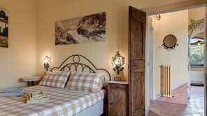 Un dormitorio con cama, mesita de noche, armario de madera, espejo en la pared y radiador.