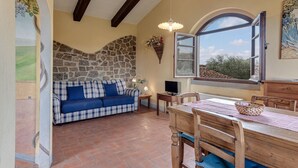 Una habitación acogedora con una pared de piedra, un sofá azul, una mesa de comedor de madera y un ventanal grande.