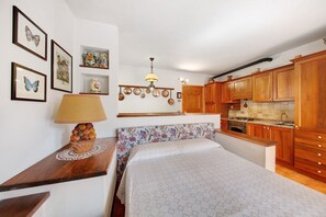 Ein Schlafzimmer mit Bett, Nachttisch, Lampe und einer Wand mit gerahmten Bildern.