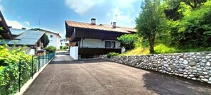 Ein Wohnhaus mit gepflasterter Auffahrt, einer Steinmauer und einem Haus mit geneigtem Dach.