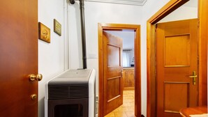 Un couloir avec un poêle à bois, des portes en bois et un sol carrelé.