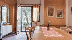 A dining area with a wooden table, chairs, a vase with flowers, and artwork on the walls. - Farmhouse 'Il Pintello - Lo Scricciolo' with Shared Pool, Wi-Fi and Air Conditioning (San Casciano VP)