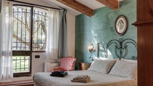 A bedroom with a bed, a chair, a window with curtains, and a wall-mounted picture. - Farmhouse 'Il Pintello - Lo Scricciolo' with Shared Pool, Wi-Fi and Air Conditioning (San Casciano VP)