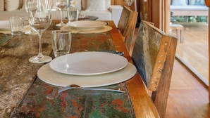 Un comedor con una mesa de madera dispuesta para una comida, un ventilador de techo y vistas al exterior.