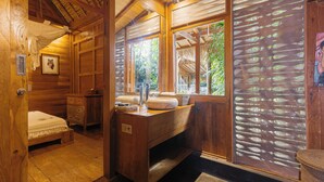Una habitación de cabaña de madera con una cama, un escritorio de madera y una ventana con vista a la vegetación.