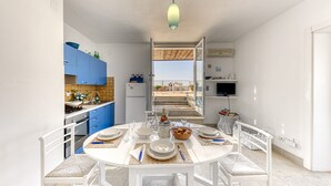 Una cucina moderna con mobili blu, un tavolo da pranzo per quattro persone e un balcone con vista.