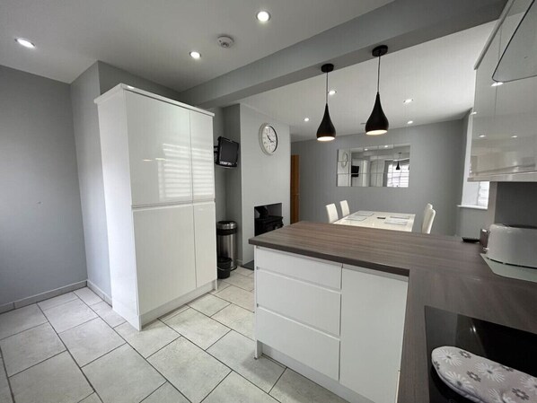 A modern kitchen with white cabinets, a wooden countertop, and pendant lighting. - Fresh and Spacious House (Denbighshire)