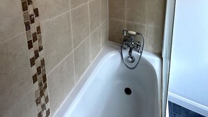 Eine Dusche mit Handbrause, einer fest installierten Bedienpanel und einer Badewanne mit Wasserhahn.
