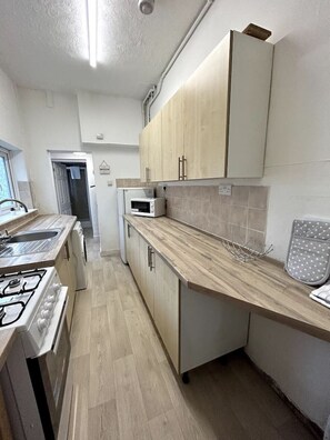 A modern kitchen with a gas stove, microwave, and wooden cabinets.