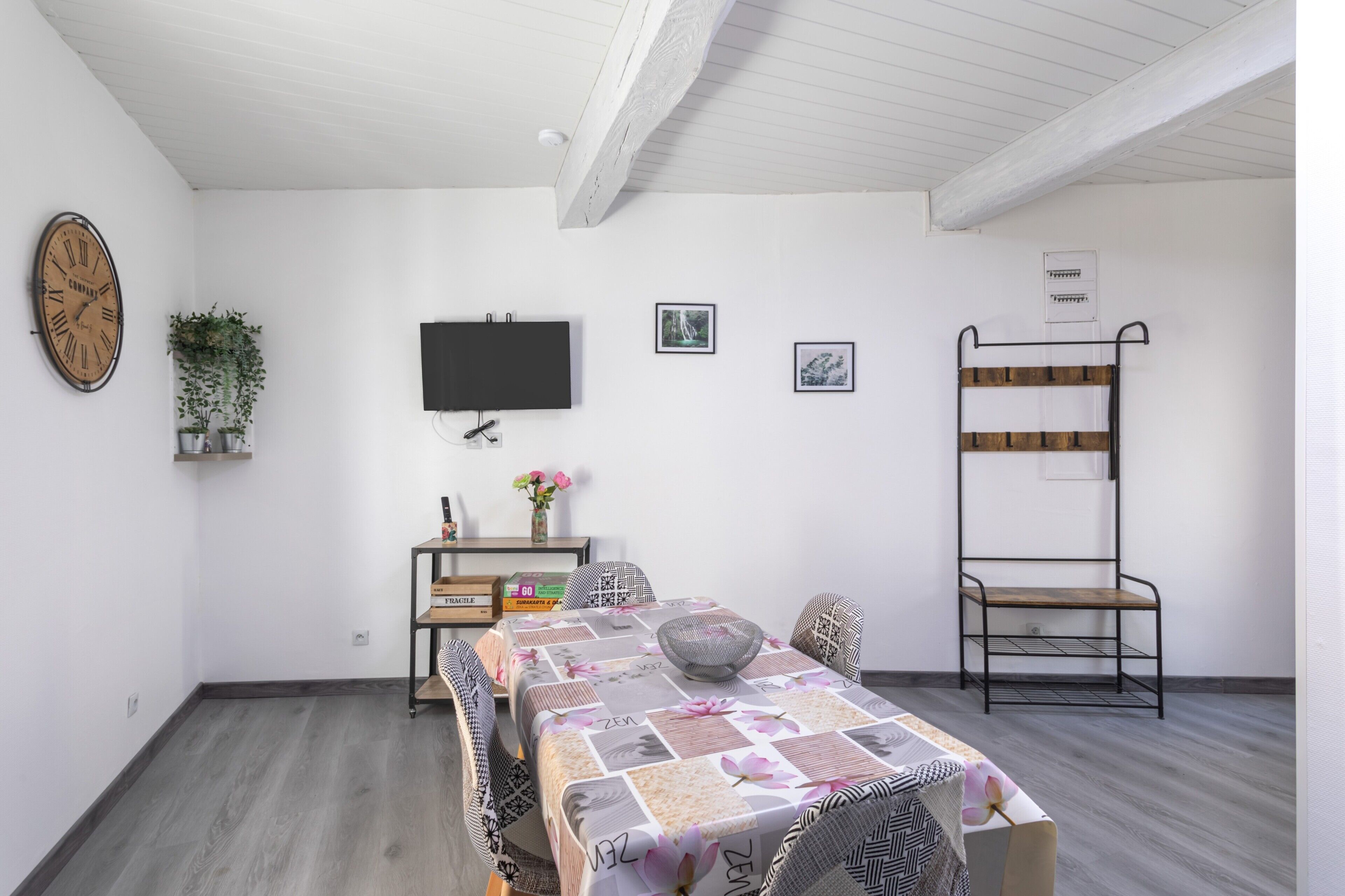 A room with a table, chairs, a TV, a plant, and a bunk bed.