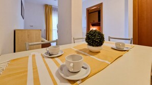 A dining area with a table set for two, a potted plant, and a small table with a cup and saucer. - Modern Residence Flat With Balcony-beahost (San Michele al Tagliamento)