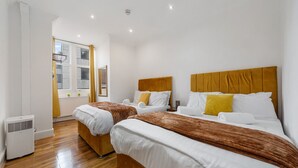 Une chambre d’hôtel avec deux lits, des têtes de lit en bois, du linge de lit blanc et une fenêtre donnant sur un beau paysage.