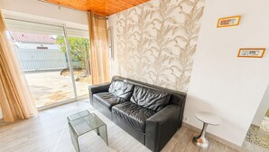 A modern living room with a leather sofa, a glass coffee table, and a patterned wallpaper. - Renovated House with Garden, Near Beach, Sleeps 4, Pet-Friendly, Private Parking (La Tranche-sur-Mer)