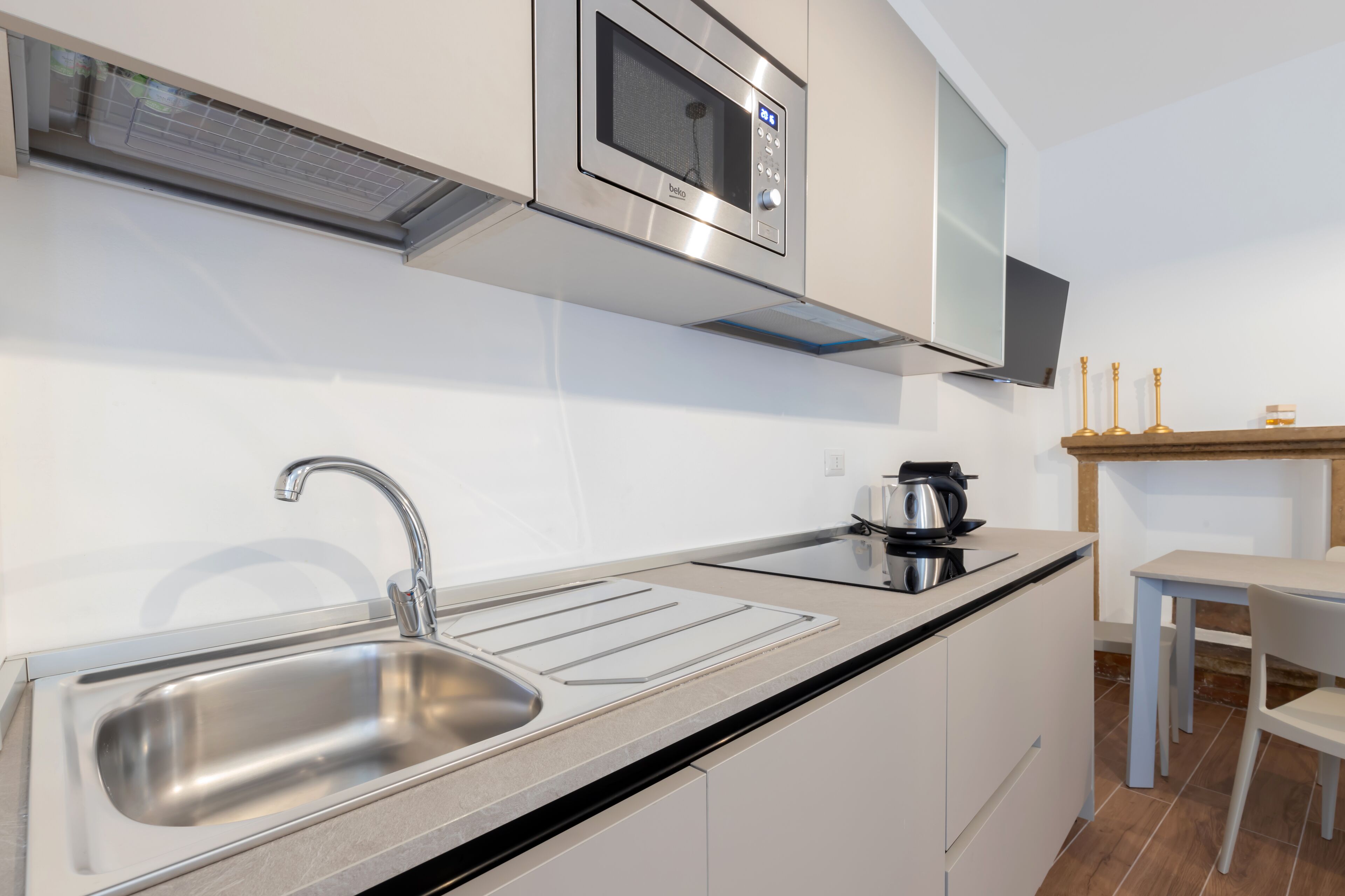 A modern kitchen with a stainless steel sink, a microwave, and a kettle on the counter.