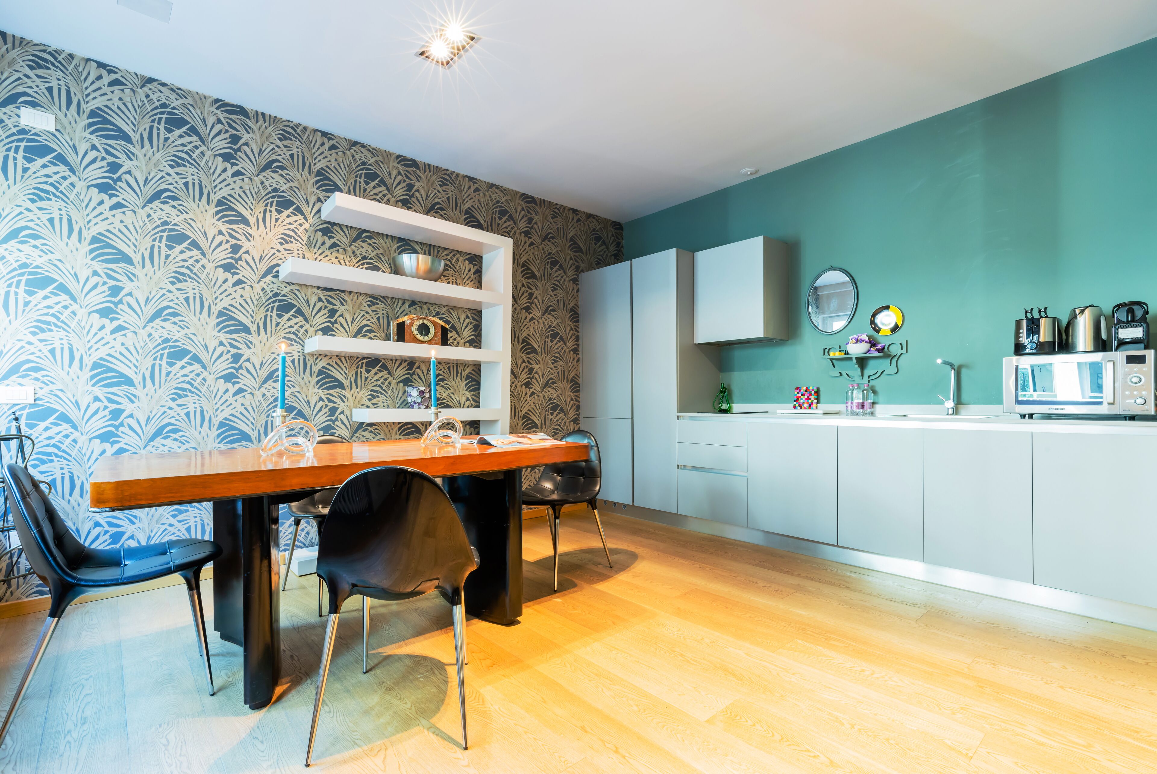 Una cocina moderna con una mesa de comedor de madera, sillas negras y un papel pintado azul y blanco.