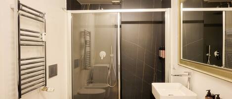 Une salle de bain moderne avec une douche à parois de verre, un lavabo blanc et un porte-serviettes.
