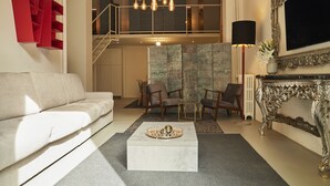 A modern living room with a white sofa, a coffee table, and a fireplace with an ornate mantel. - Milan Retreats Brera (Milan)