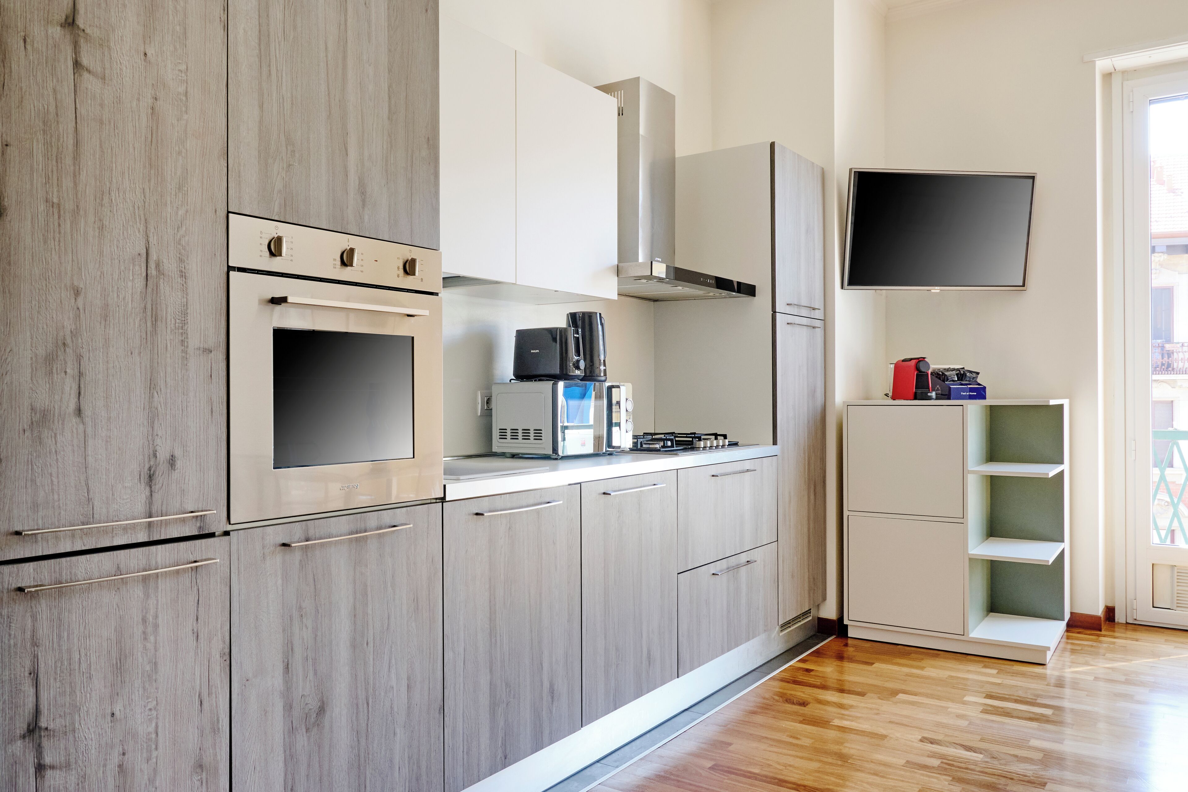Uma cozinha moderna com armários de madeira, forno embutido, micro-ondas e máquina de café.