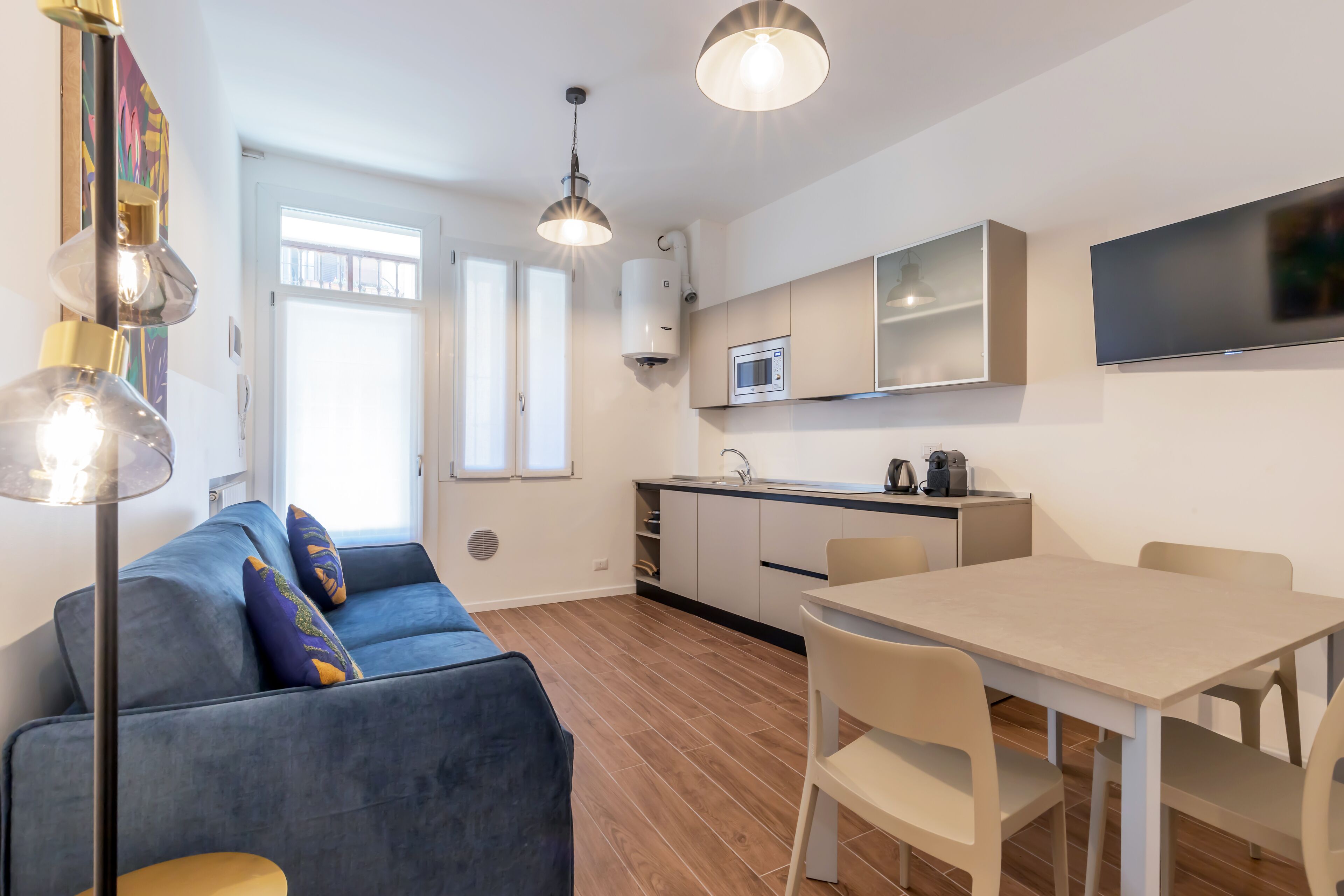A modern living space with a sofa, a dining table, and a kitchen area.