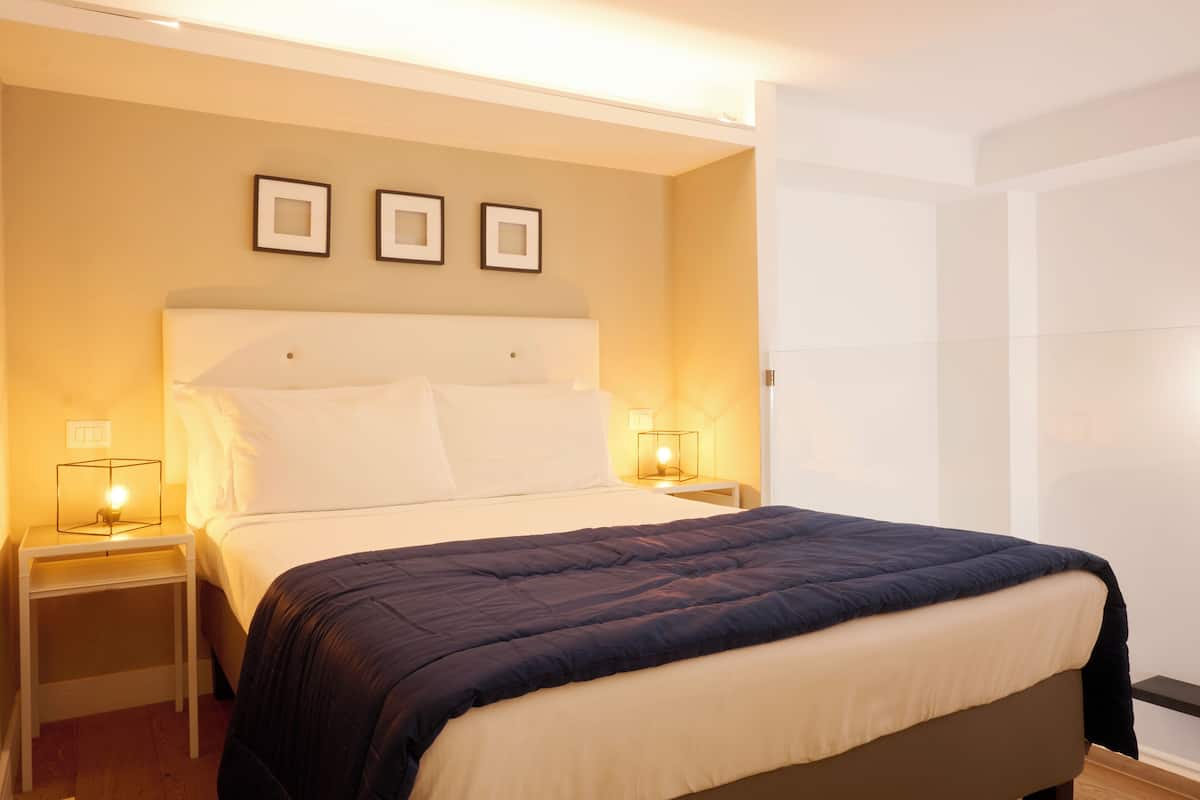 A hotel room with a large bed, two bedside tables with lamps, and three framed pictures on the wall.