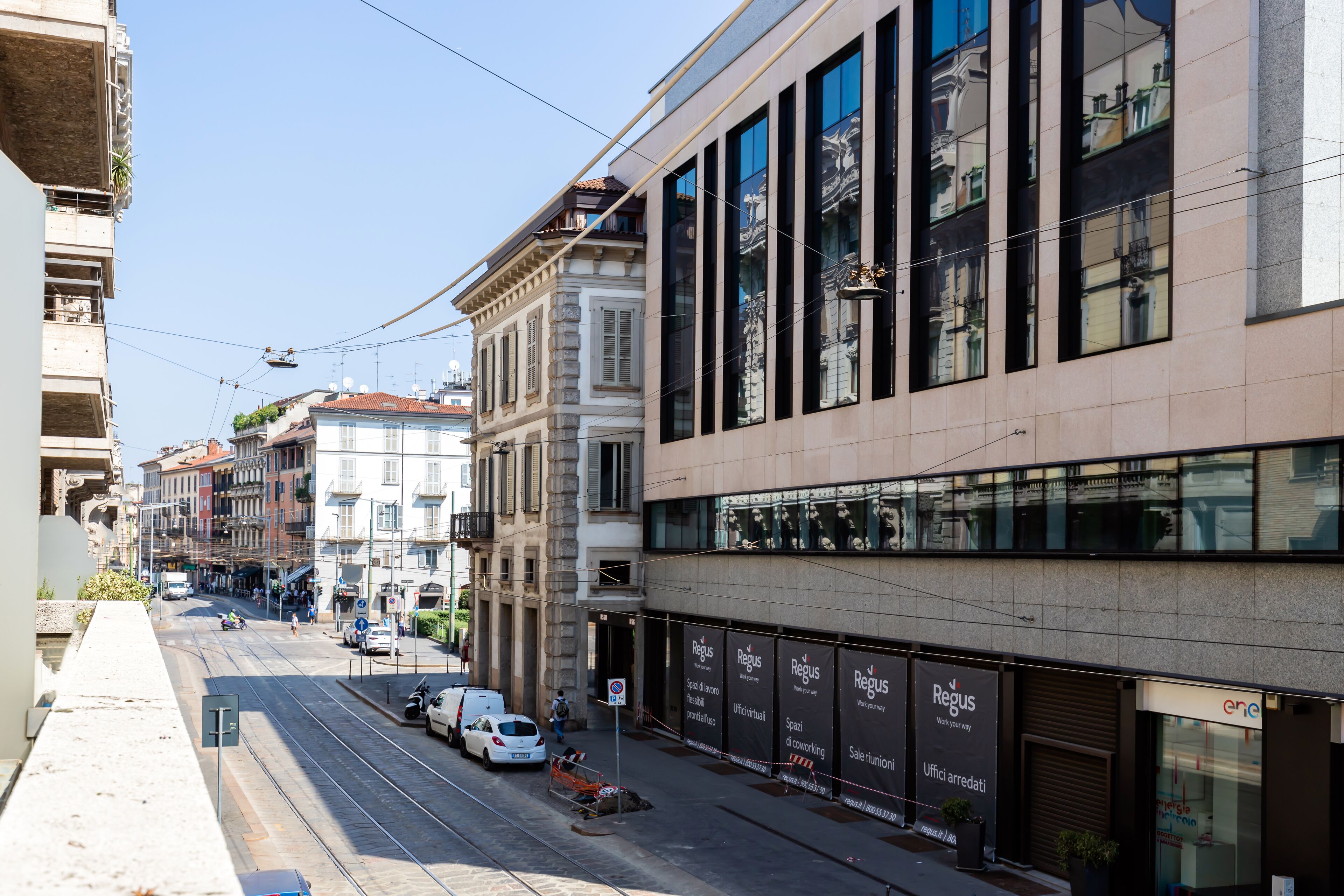 Eine Straße mit einem modernen Gebäude, das große Fenster und ein Schild für 'Regus' zeigt.