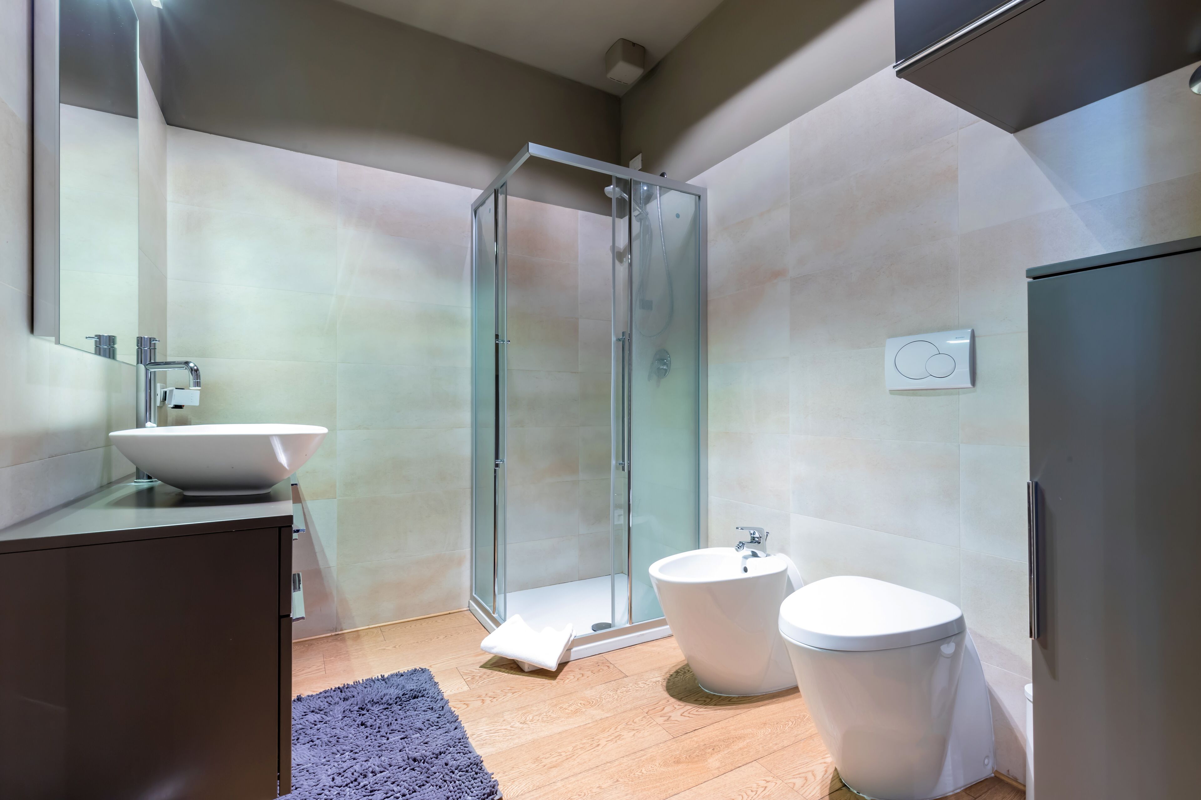 A modern bathroom with a glass-enclosed shower, a freestanding bathtub, and a toilet.
