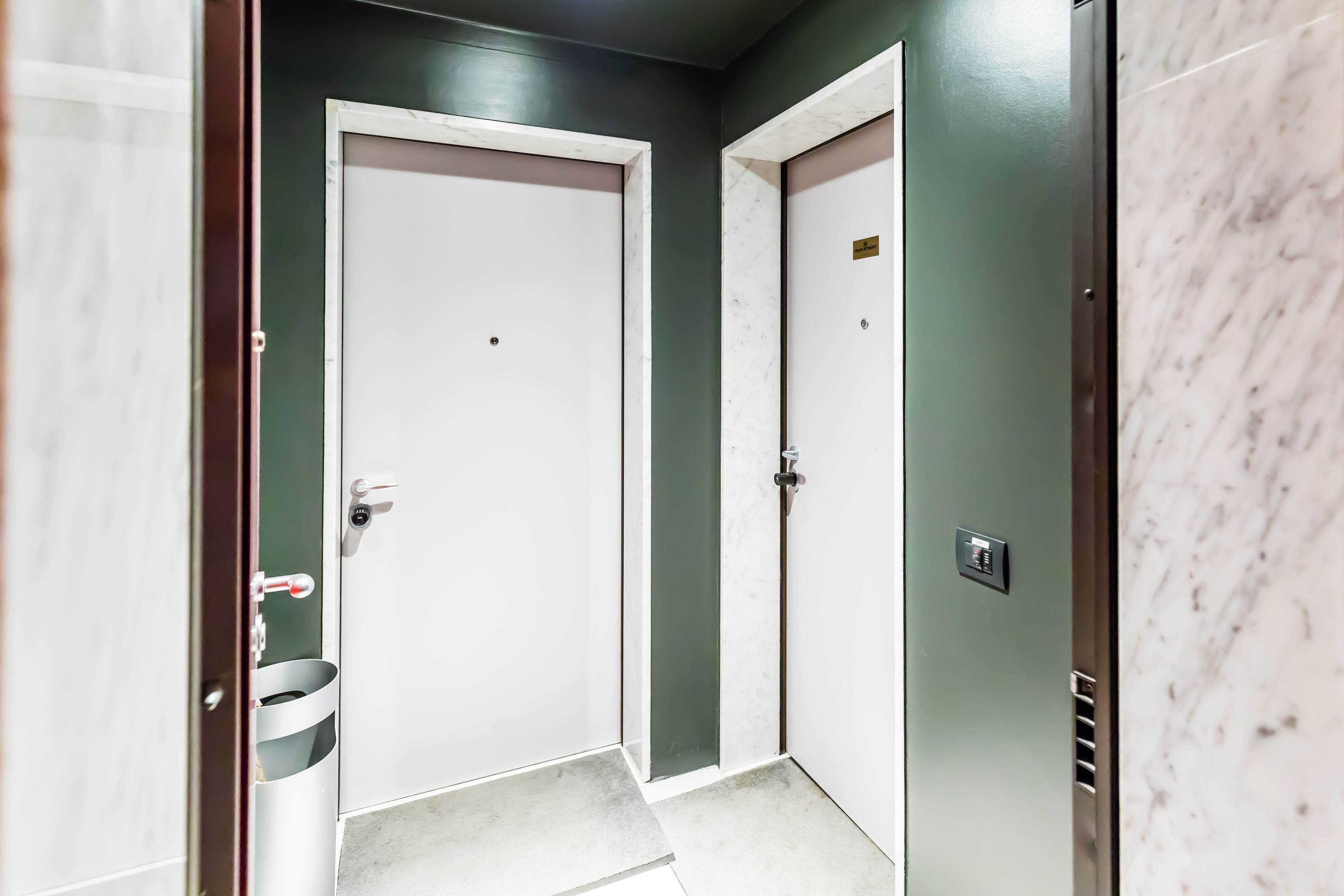 A hallway with two doors, one with a metal handle and the other with a keyhole.