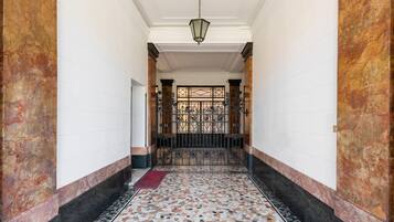 A hallway with a tiled floor, a red carpet, and a metal gate at the end.