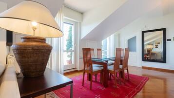 A dining area with a table, chairs, a lamp, and a red rug.