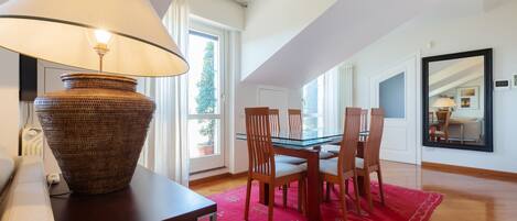 Un coin repas comprenant une table, des chaises, une lampe et un tapis rouge.