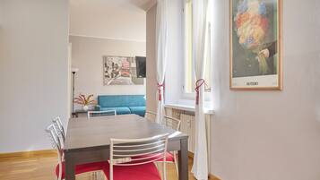 A dining area with a wooden table and chairs, a blue sofa, and a framed picture on the wall.