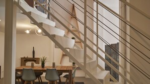 A modern interior with a wooden dining table, four chairs, and a staircase with a wooden ladder. - Milan Retreats Brera (Milan)