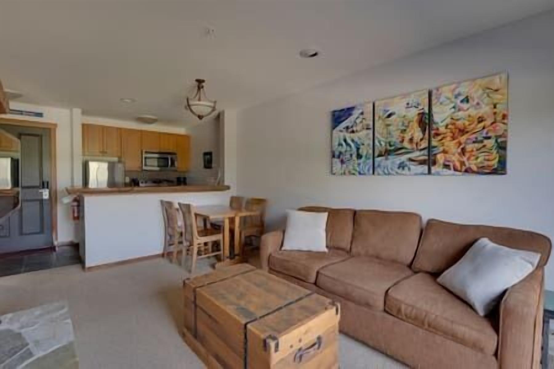 Uma sala de estar com um sofá marrom, uma mesa de centro de madeira e um quadro na parede.