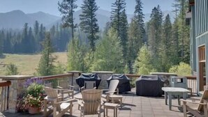 A patio with outdoor furniture, a covered grill, and a view of a forest and mountains. - Ski In-Out Location / 1 Bed / Hot Tubs, Pool & Gym (Fernie)