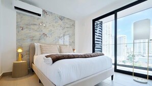 A modern bedroom with a large bed, a city view, and a marble-patterned wall. - w* | High-end 1BR in San Francisco w/ Balcony (Panamá)
