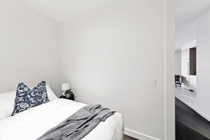 A bedroom with a bed, pillows, a bedside table, and a lamp.