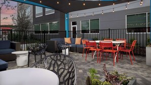 An outdoor patio with seating, tables, and string lights. - Tru by Hilton Jacksonville West I 295 (Jacksonville)